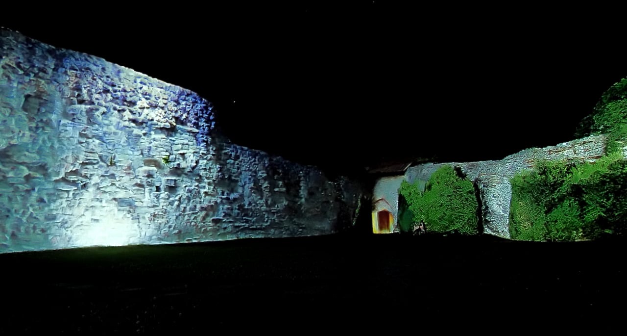 The stone walls of the Gebhardsberg castle ruin above Bregenz lit by a white and blue projection mapping at night