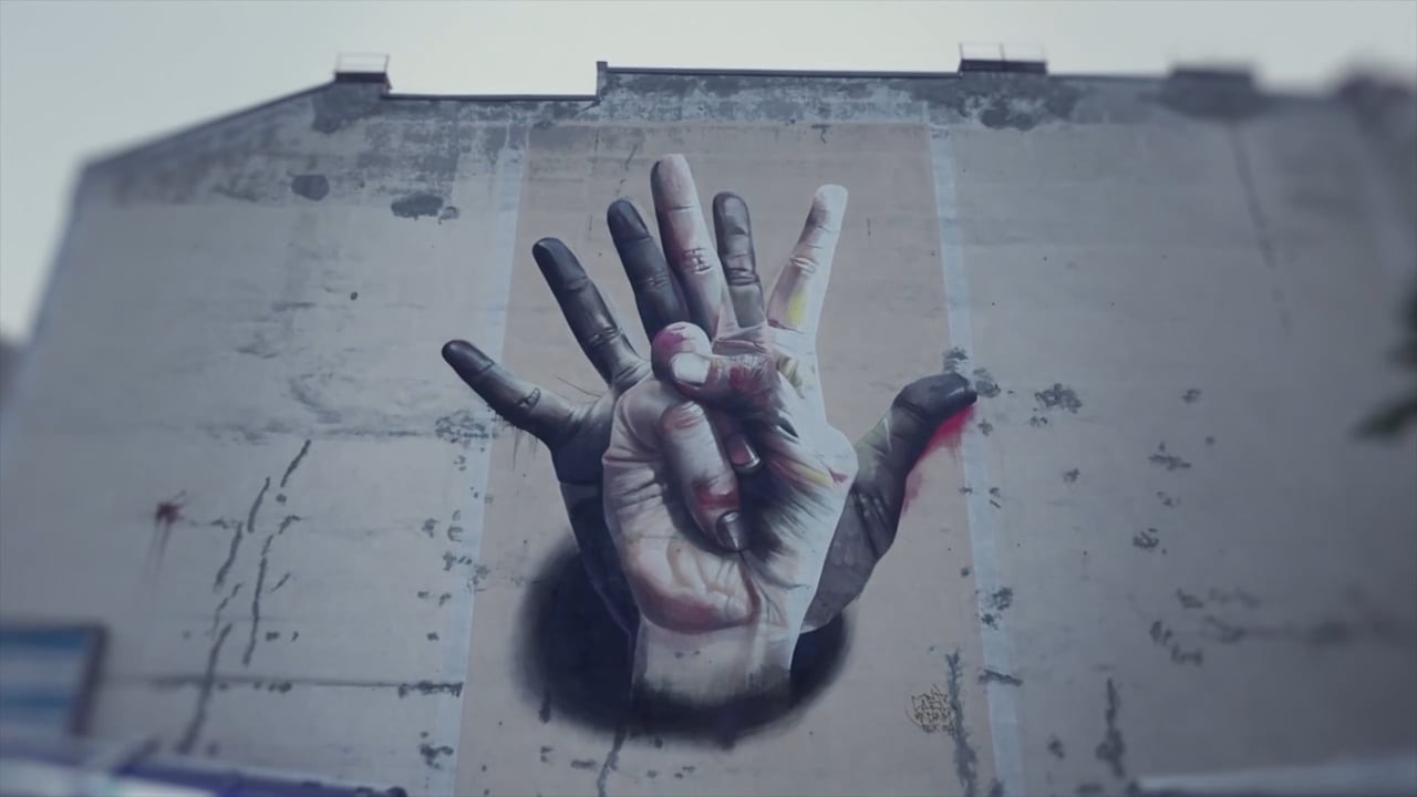 A large mural of an open hand on a building wall, animated with projection mapping