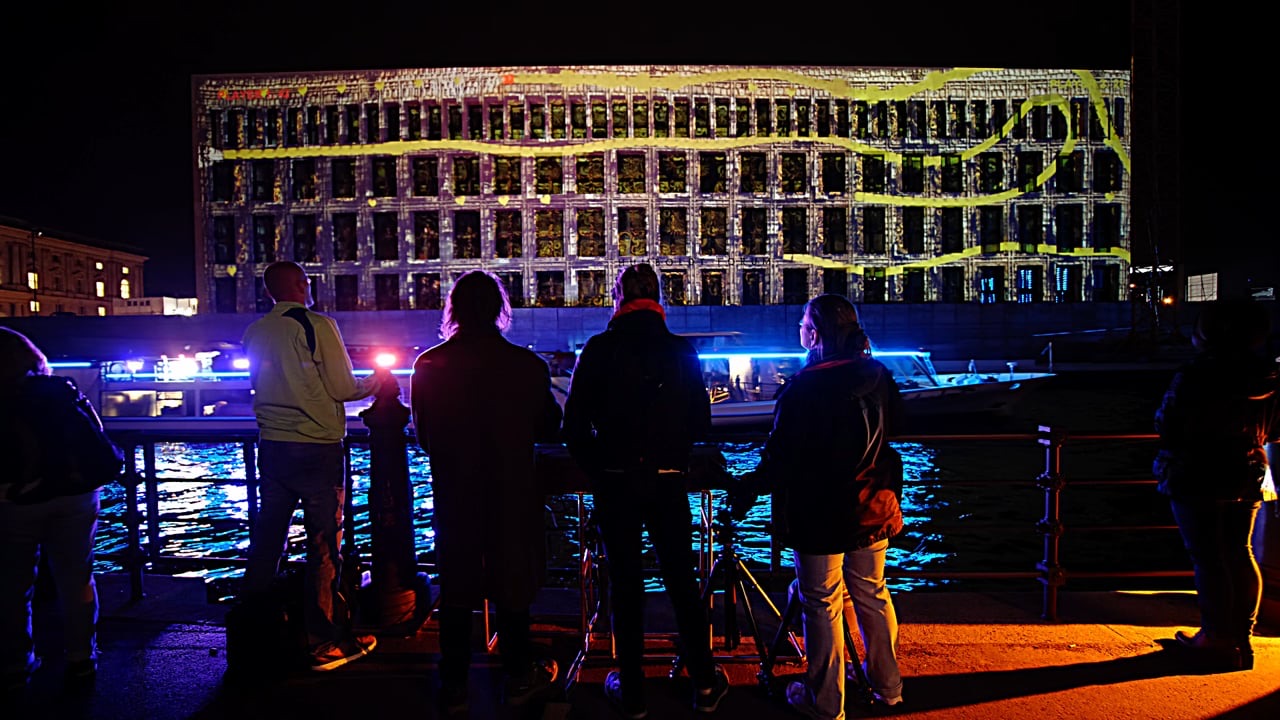 Visitors playing a projected multiplayer game on the façade of the Humboldt Forum in Berlin at night
